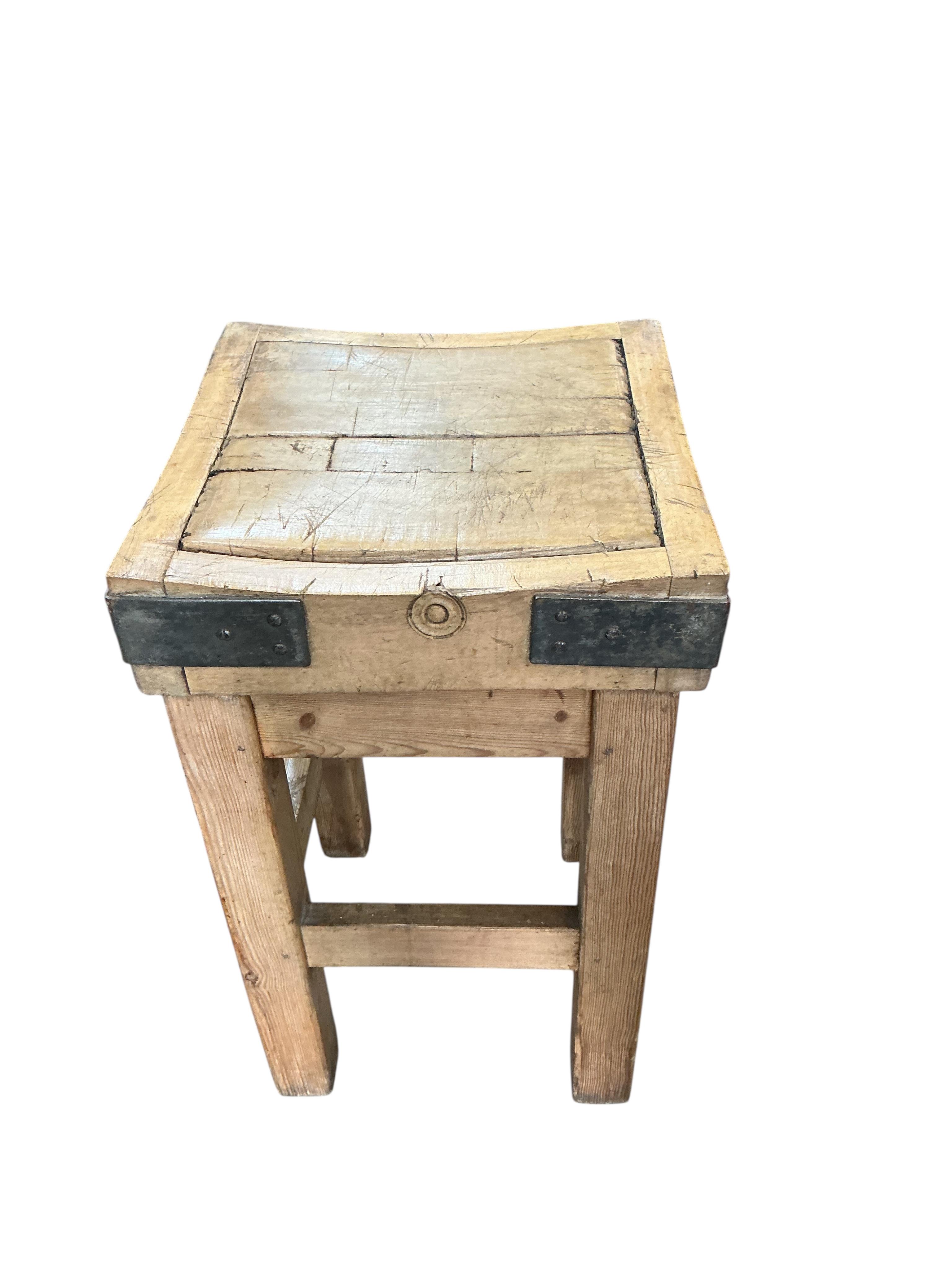 A small iron bound butcher’s block on stand bears metal plaque 